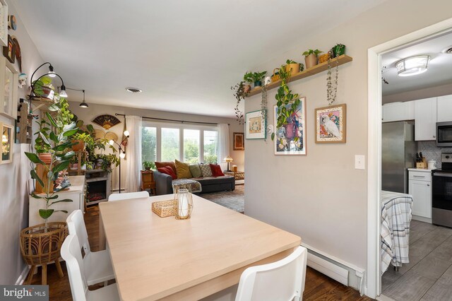 dining room with dark wood-type flooring, a baseboard radiator, and visible vents