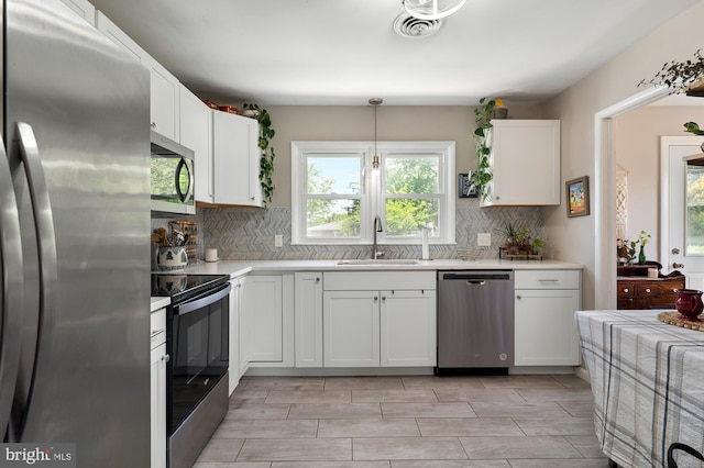 kitchen with light countertops, white cabinets, tasteful backsplash, a sink, and stainless steel appliances