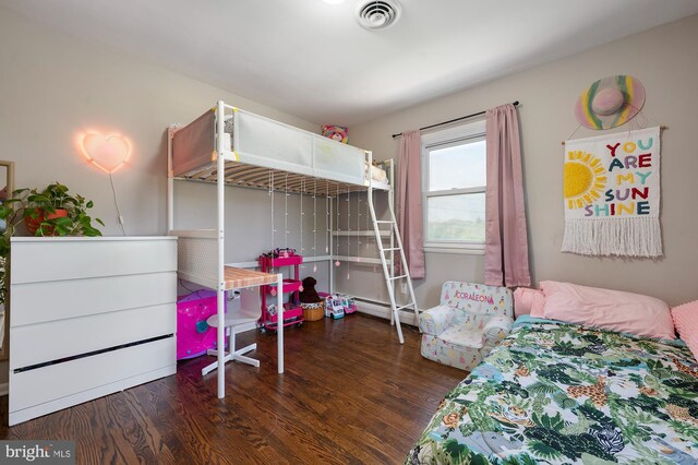 bedroom featuring a baseboard radiator, wood finished floors, and visible vents