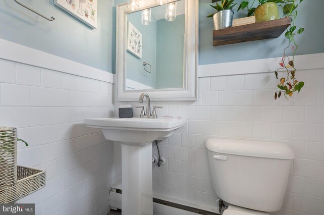 bathroom with toilet, tile walls, and wainscoting