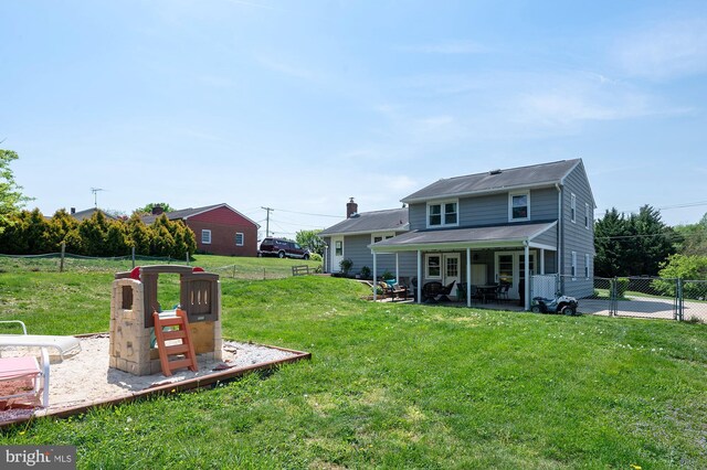 back of house featuring a yard, a patio, fence, and a chimney