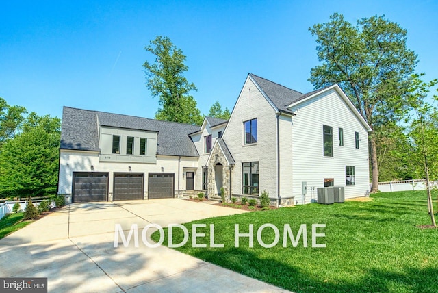 view of front of house with a garage, fence, a front yard, central AC unit, and concrete driveway