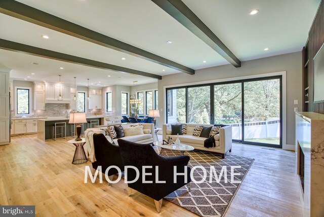 living area with light wood-style floors, recessed lighting, and beam ceiling