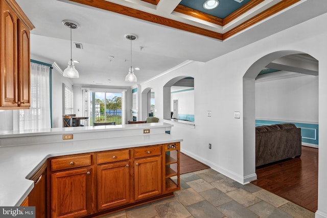 kitchen with crown molding, pendant lighting, a peninsula, open floor plan, and light countertops