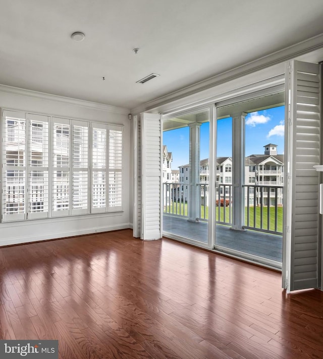 empty room featuring crown molding, visible vents, and wood finished floors