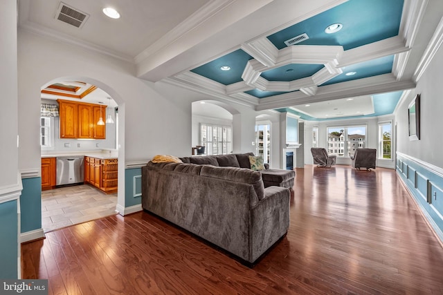 living room featuring visible vents, ornamental molding, and arched walkways