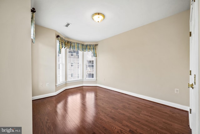 unfurnished room featuring baseboards, wood finished floors, and visible vents