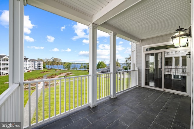 unfurnished sunroom featuring a water view, beam ceiling, and a healthy amount of sunlight