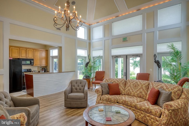 living area with a notable chandelier, a wealth of natural light, and a towering ceiling