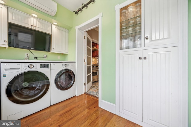 2410 S Camac St, Philadelphia, PA 19148 - washroom with cabinet space, a wall mounted AC, washing machine and dryer, and light wood-type flooring