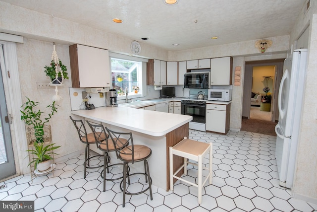 kitchen featuring white appliances, light flooring, a sink, and a peninsula