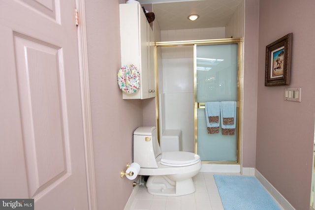 bathroom featuring tile patterned flooring, a shower stall, toilet, and baseboards