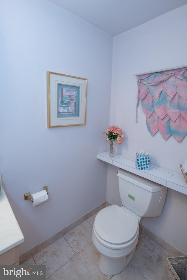 bathroom with toilet, vanity, baseboards, and tile patterned floors