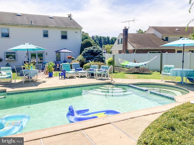 view of swimming pool featuring a patio area, fence, and a pool with connected hot tub