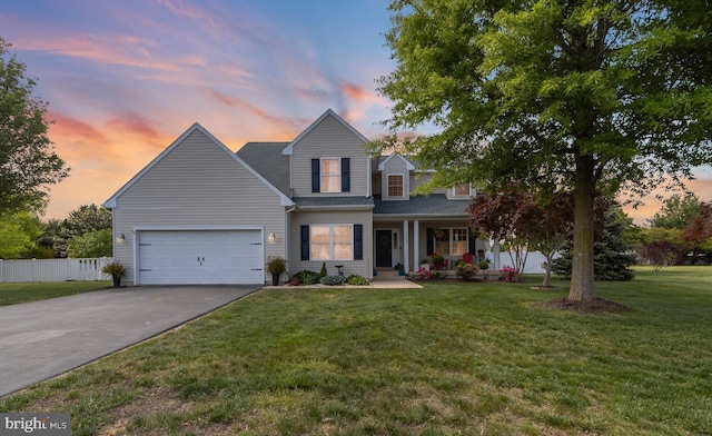 traditional-style home featuring fence, an attached garage, aphalt driveway, a front yard, and covered porch