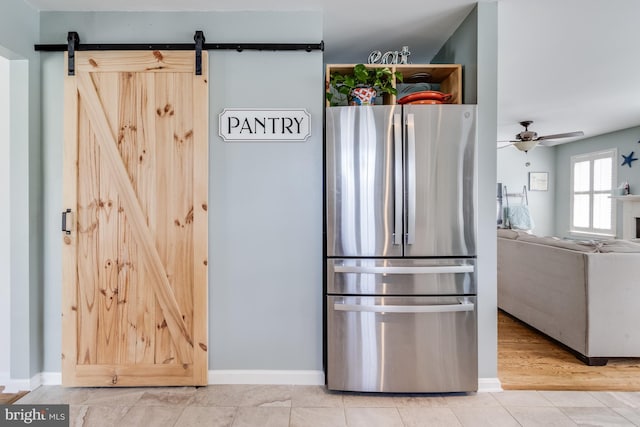 kitchen with baseboards, ceiling fan, freestanding refrigerator, and a barn door