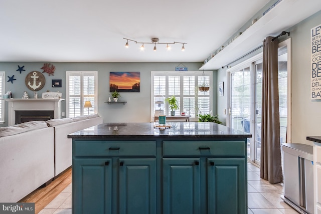 kitchen featuring light tile patterned floors, dark countertops, a kitchen island, and blue cabinets