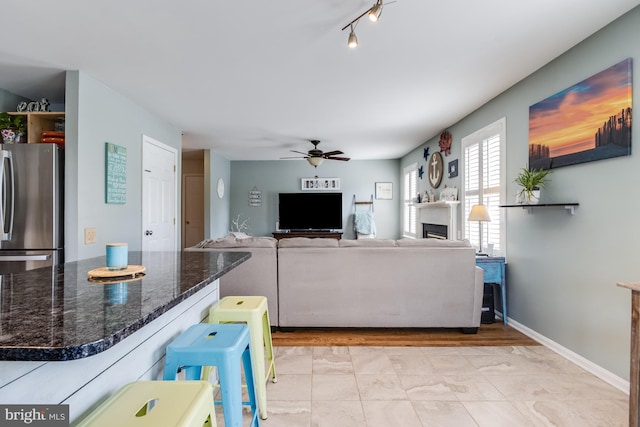 living room featuring baseboards and ceiling fan