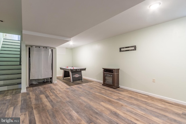 finished basement featuring stairway, baseboards, and wood finished floors