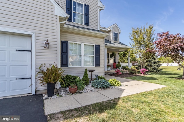 view of exterior entry with a porch, a yard, and a garage