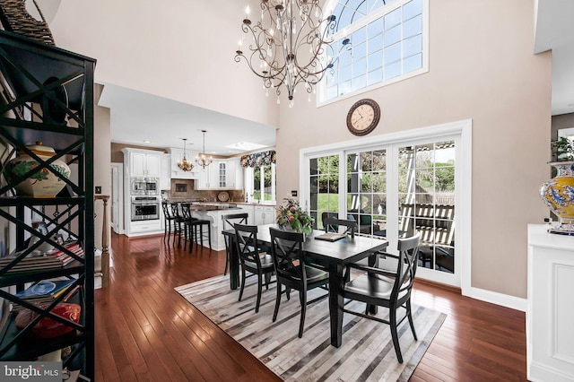 dining space featuring a high ceiling, an inviting chandelier, dark wood-style floors, and baseboards