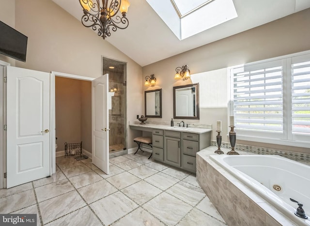 bathroom featuring vaulted ceiling with skylight, vanity, a jetted tub, and a stall shower