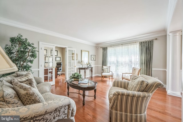 living room with ornamental molding, light wood finished floors, french doors, and ornate columns