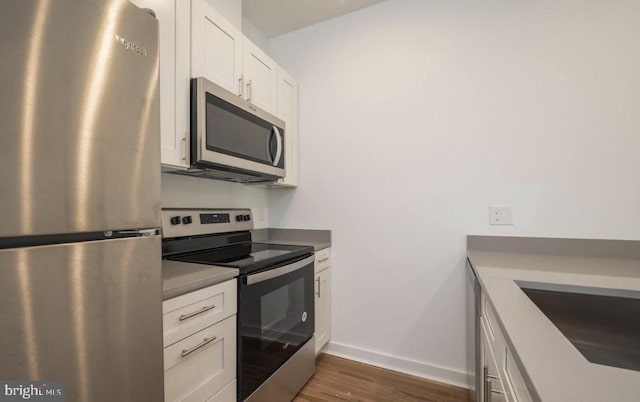 727 N 39th St, Philadelphia, PA 19104 - kitchen featuring wood finished floors, baseboards, white cabinetry, a sink, and appliances with stainless steel finishes