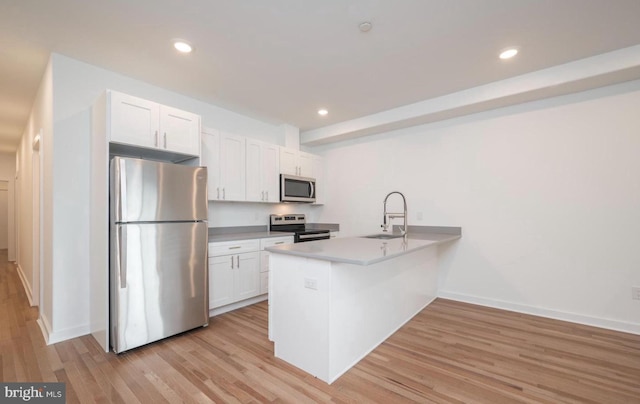 727 N 39th St, Philadelphia, PA 19104 - kitchen with appliances with stainless steel finishes, light wood-type flooring, a sink, white cabinets, and a peninsula