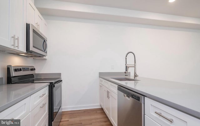 727 N 39th St, Philadelphia, PA 19104 - kitchen with appliances with stainless steel finishes, a sink, light countertops, white cabinetry, and light wood-type flooring