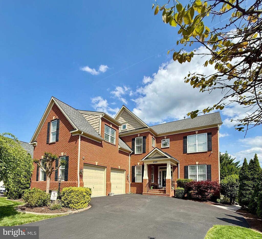 view of property featuring a garage, aphalt driveway, and brick siding