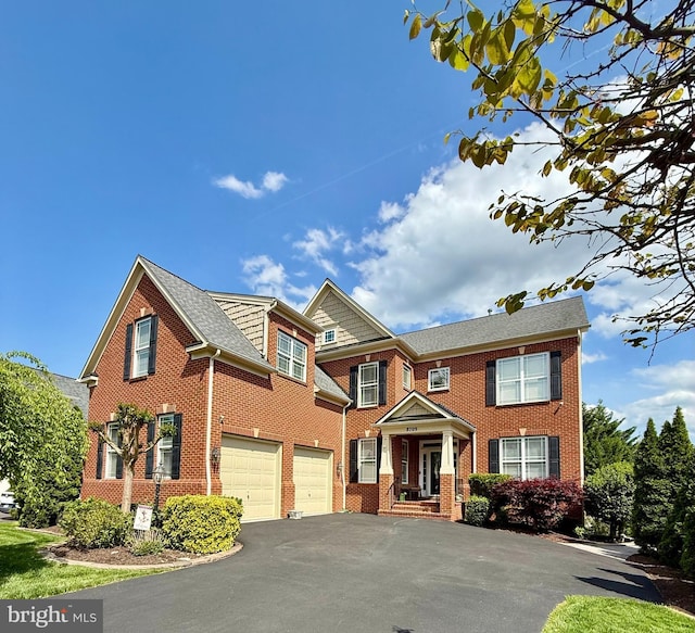 view of property featuring a garage, aphalt driveway, and brick siding