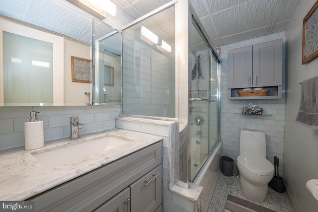 1030 E Lancaster Ave Unit 330, Bryn Mawr, PA 19010 - bathroom with tile walls, bath / shower combo with glass door, toilet, tile patterned floors, and vanity