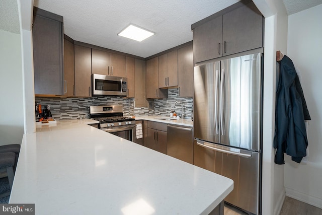 1030 E Lancaster Ave Unit 330, Bryn Mawr, PA 19010 - kitchen featuring a sink, stainless steel appliances, a textured ceiling, light countertops, and tasteful backsplash