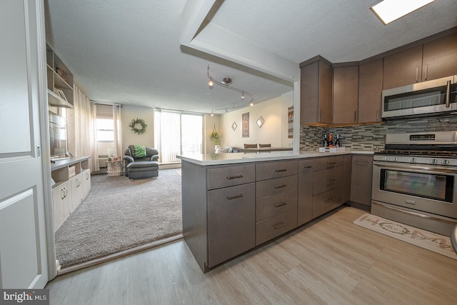 1030 E Lancaster Ave Unit 330, Bryn Mawr, PA 19010 - kitchen with a peninsula, tasteful backsplash, light wood-style flooring, open floor plan, and appliances with stainless steel finishes