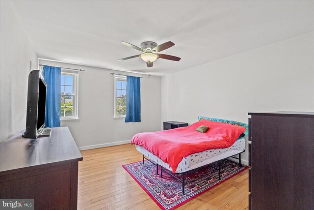 bedroom with light wood-style floors, baseboards, and ceiling fan
