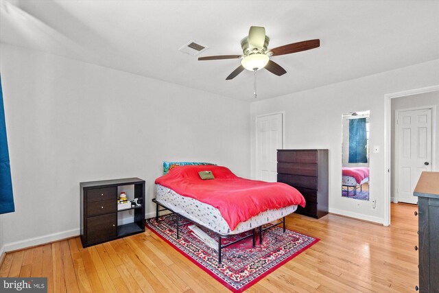 bedroom with ceiling fan, baseboards, visible vents, and wood finished floors