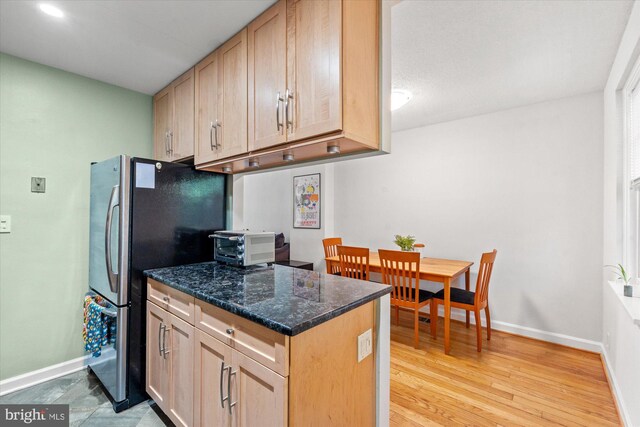 kitchen with baseboards, freestanding refrigerator, and light brown cabinetry