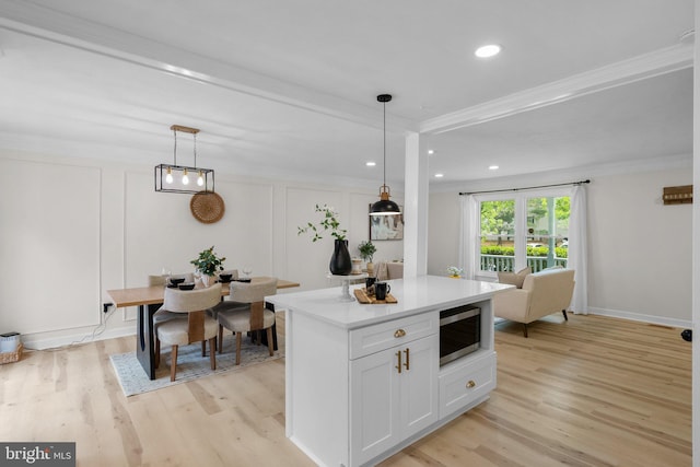 13405 Wisteria Dr, Germantown, MD 20874 - kitchen featuring stainless steel microwave, light wood finished floors, ornamental molding, light countertops, and white cabinetry
