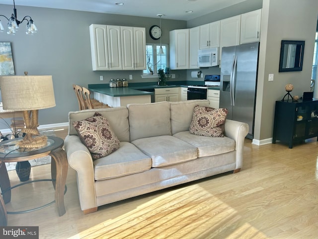living area featuring baseboards, recessed lighting, light wood-style floors, and a notable chandelier