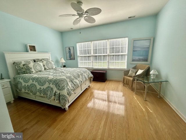 bedroom with baseboards, a ceiling fan, wood finished floors, and visible vents