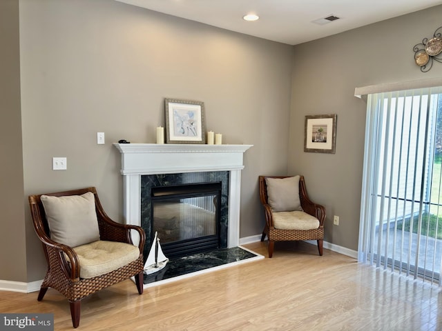 sitting room with recessed lighting, baseboards, wood finished floors, a high end fireplace, and visible vents