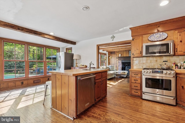 kitchen featuring light wood-style floors, a center island with sink, recessed lighting, a sink, and stainless steel appliances