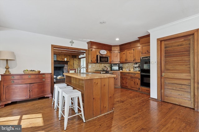 kitchen with dobule oven black, backsplash, dark wood finished floors, a sink, and stainless steel microwave