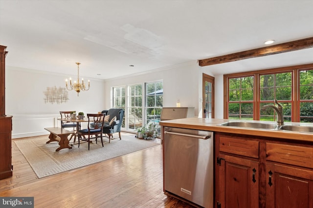 kitchen featuring decorative light fixtures, stainless steel dishwasher, a sink, wood-type flooring, and a chandelier