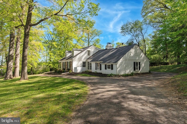 view of property exterior featuring aphalt driveway, a yard, and a chimney