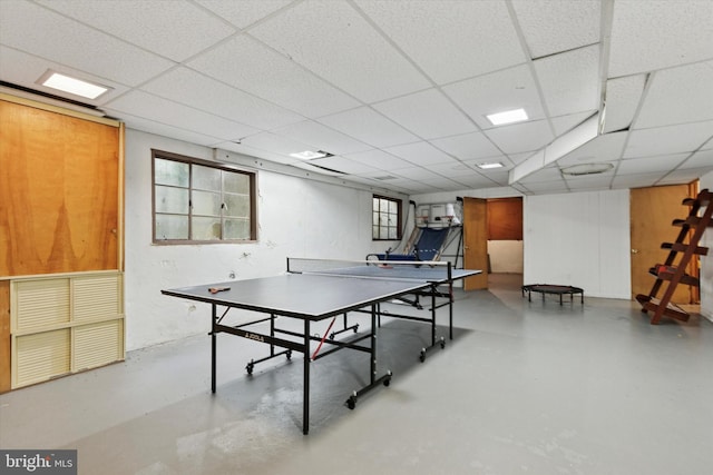 recreation room with concrete flooring, a drop ceiling, and a healthy amount of sunlight