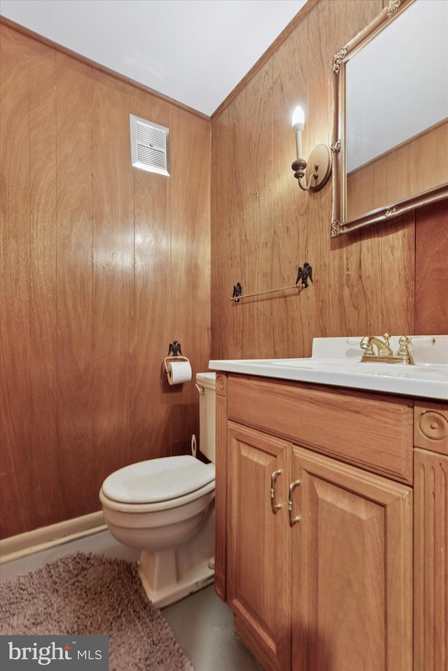 bathroom featuring visible vents, wood walls, toilet, and vanity