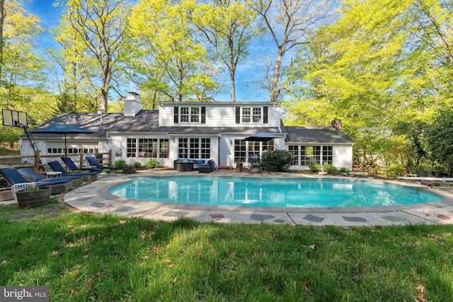 rear view of house featuring an outdoor hangout area, an outdoor pool, and a chimney