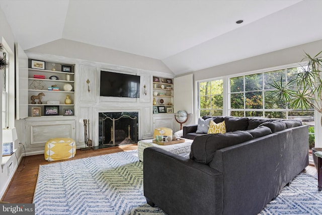 living room with a premium fireplace, built in shelves, wood finished floors, and lofted ceiling